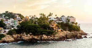 Acapulco - Blick vom Meer auf einen Felsenvorprung an der Küste bei Reisemagazin Plus