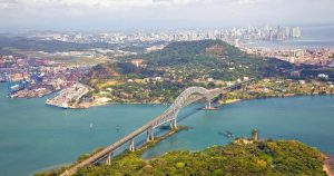 Panama - Luftaufnahme der Amerikabrücke am pazifischen Eingang zum Panamakanal mit Panama-Stadt im Hintergrund bei Reisemagazin Plus